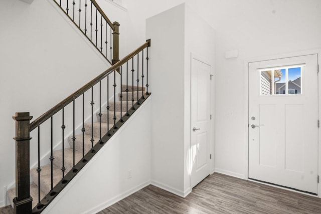 foyer entrance with a high ceiling, stairs, baseboards, and wood finished floors