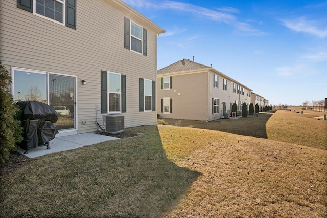 rear view of house with a patio, cooling unit, and a yard