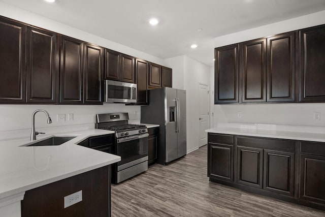 kitchen featuring dark wood-type flooring, a sink, recessed lighting, stainless steel appliances, and light countertops