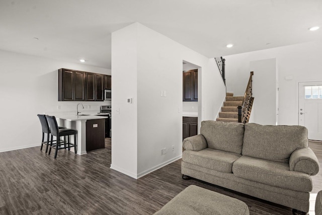living room featuring recessed lighting, dark wood finished floors, and stairs