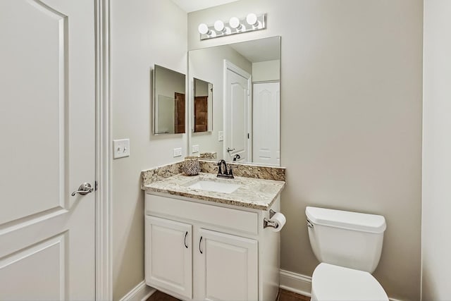 bathroom featuring vanity, toilet, and baseboards