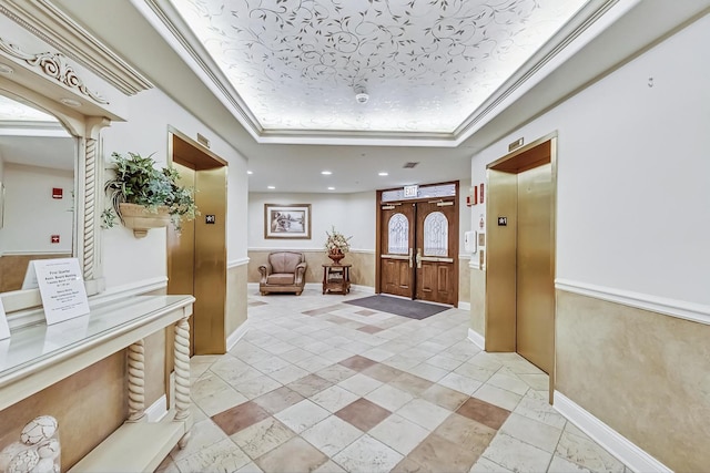 entryway featuring crown molding, a tray ceiling, elevator, recessed lighting, and wainscoting