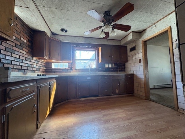 kitchen with light wood-style flooring, dark brown cabinetry, light countertops, baseboard heating, and ceiling fan