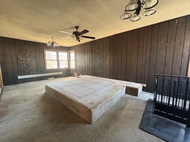 carpeted bedroom featuring a textured ceiling, an inviting chandelier, and wood walls