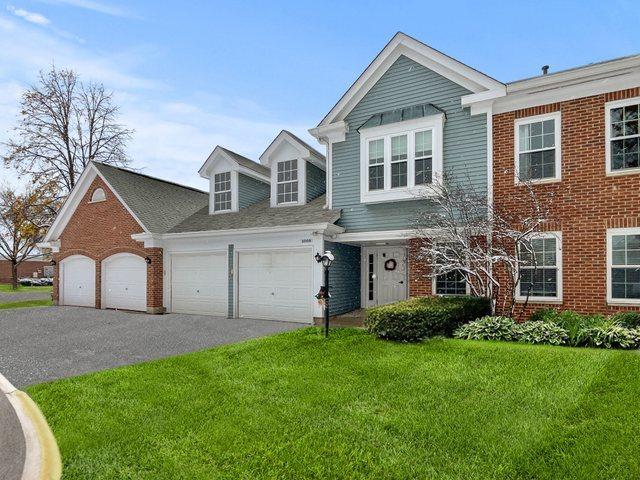 view of front of home with brick siding, a garage, driveway, and a front yard