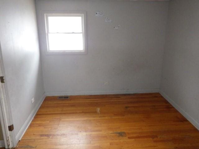 empty room featuring visible vents, light wood-style flooring, and baseboards