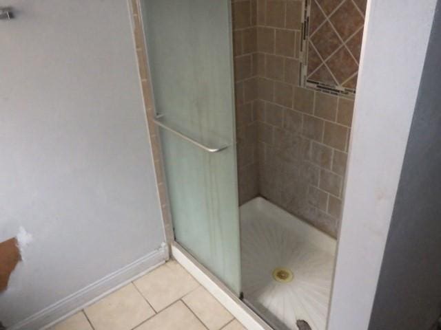 bathroom featuring tile patterned flooring, baseboards, and a stall shower