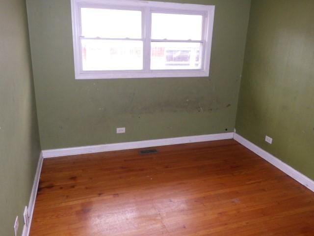 unfurnished room with baseboards and wood finished floors