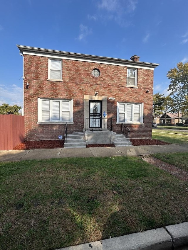 view of front of home featuring a front lawn, fence, brick siding, and a chimney