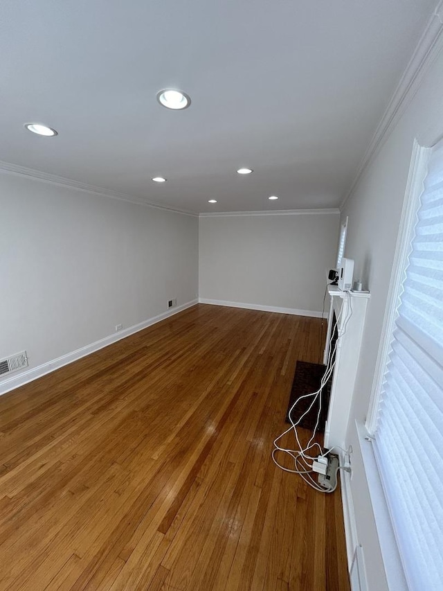 empty room with baseboards, wood finished floors, visible vents, and ornamental molding