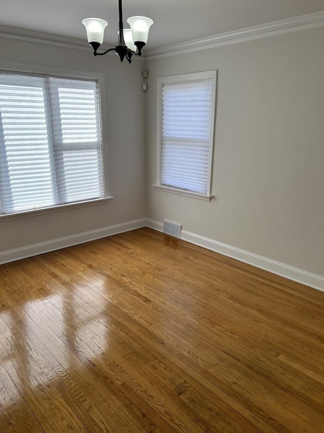 unfurnished room featuring baseboards, ornamental molding, visible vents, and a notable chandelier