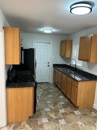 kitchen featuring a sink, dark countertops, and stone finish flooring