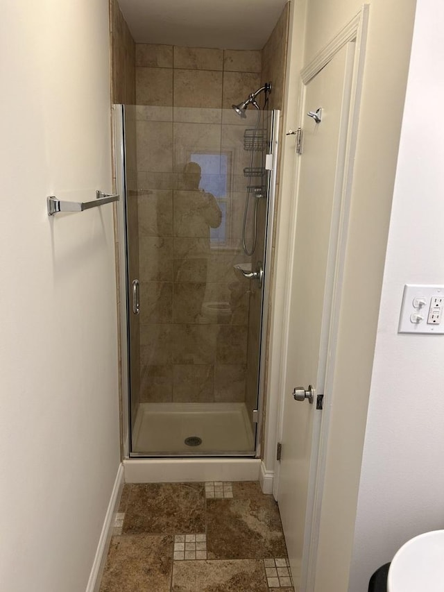 full bathroom featuring a stall shower and baseboards