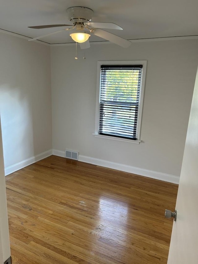 empty room featuring baseboards, visible vents, wood finished floors, and ceiling fan