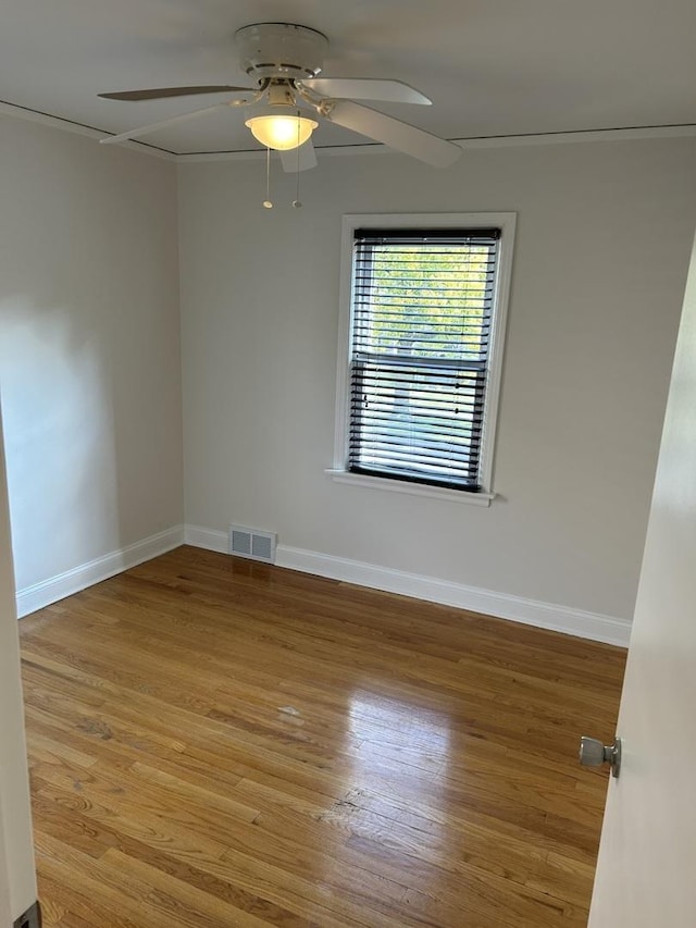 empty room featuring visible vents, baseboards, wood finished floors, and a ceiling fan