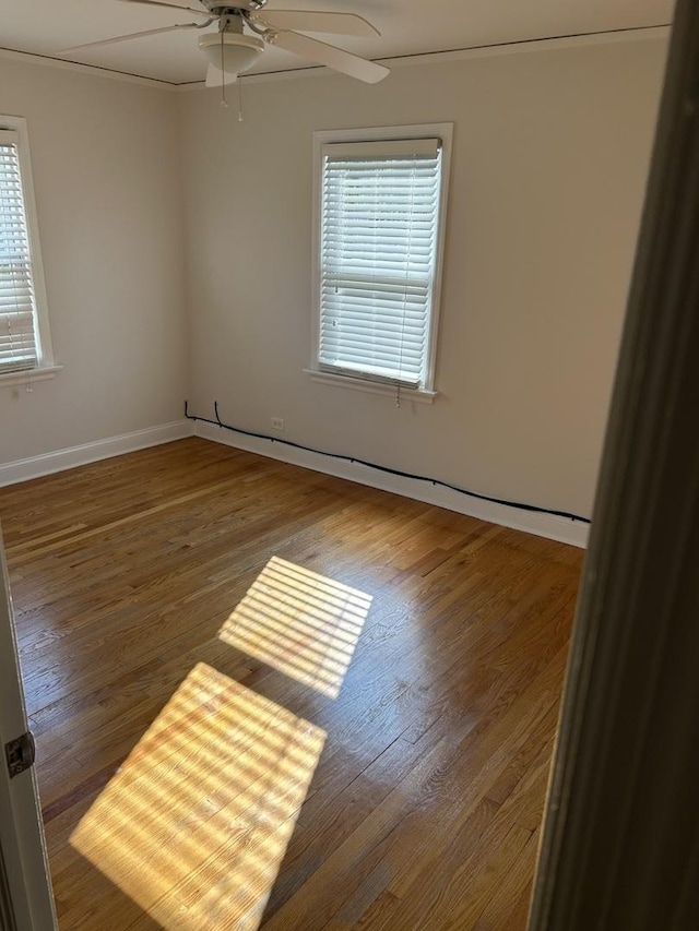 unfurnished room with wood finished floors, a ceiling fan, and baseboards