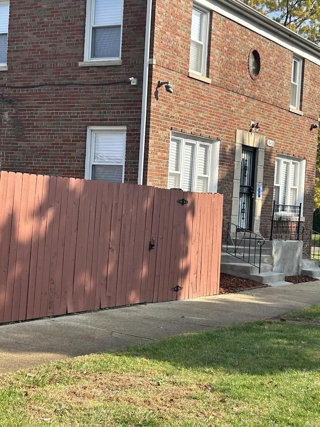 view of property exterior with brick siding and fence