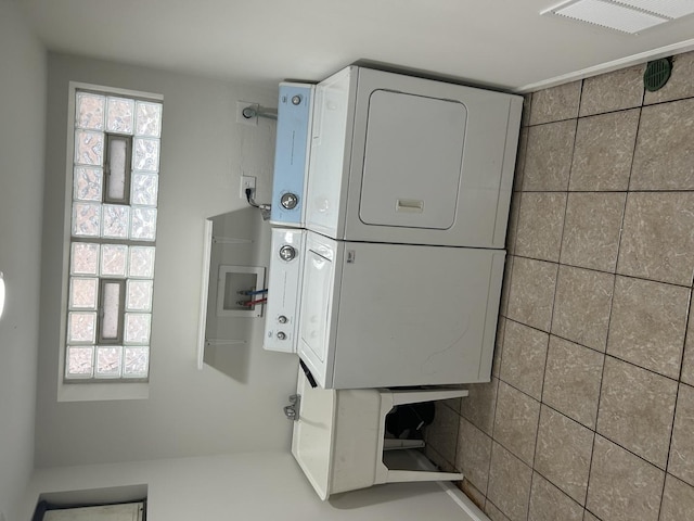 laundry area with laundry area, stacked washer / dryer, and visible vents