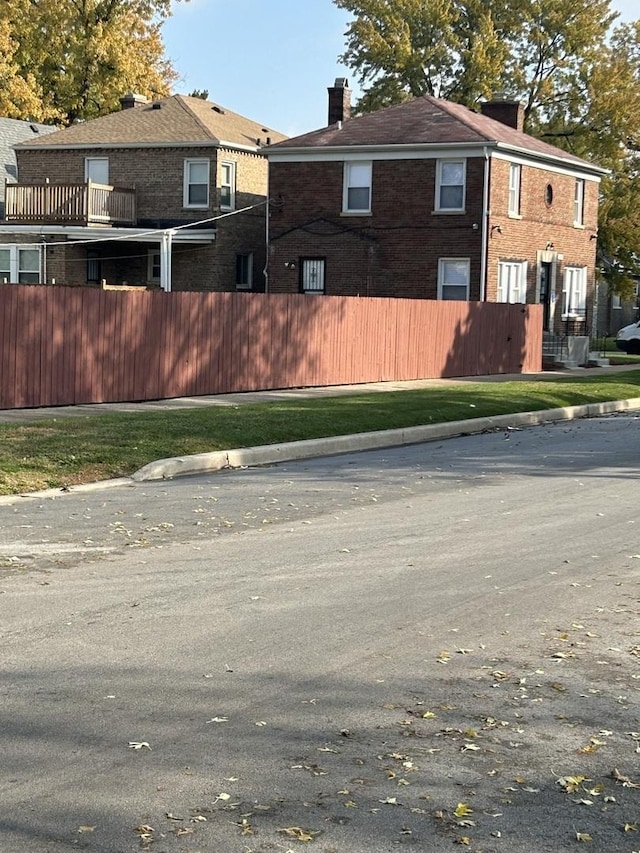 view of home's exterior featuring brick siding, a chimney, and fence