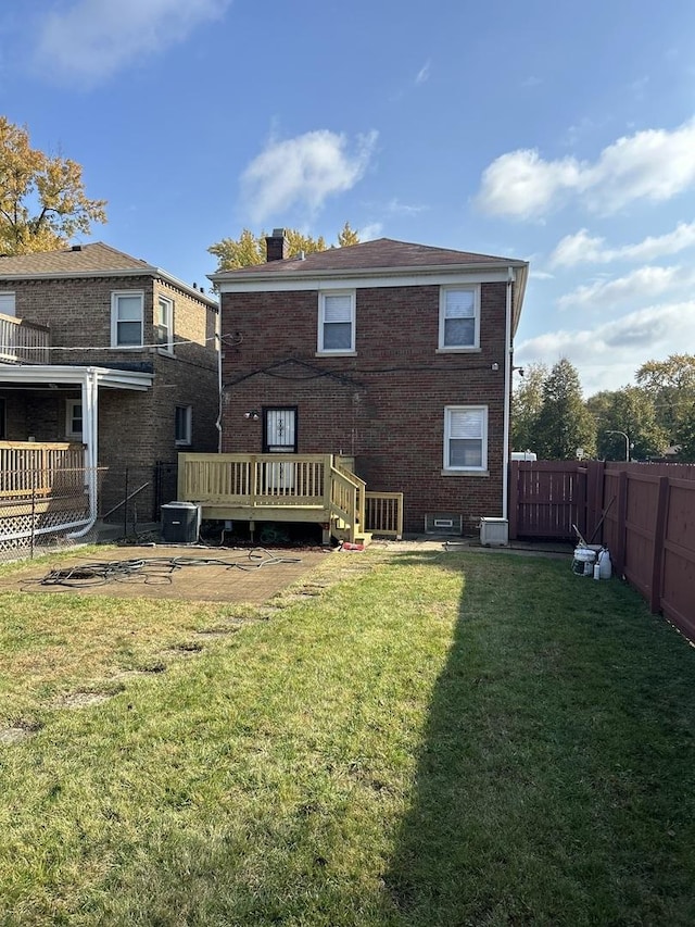 rear view of house with brick siding, a fenced backyard, and a yard