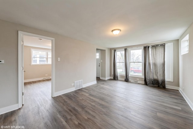 spare room featuring dark wood-style floors, visible vents, and baseboards