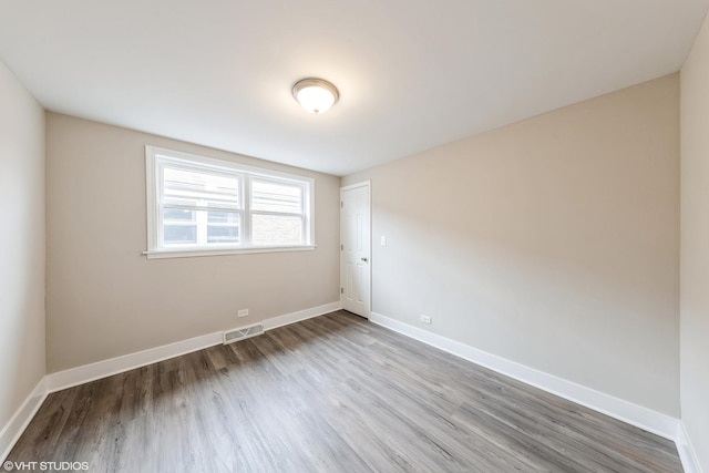 unfurnished room featuring visible vents, baseboards, and wood finished floors