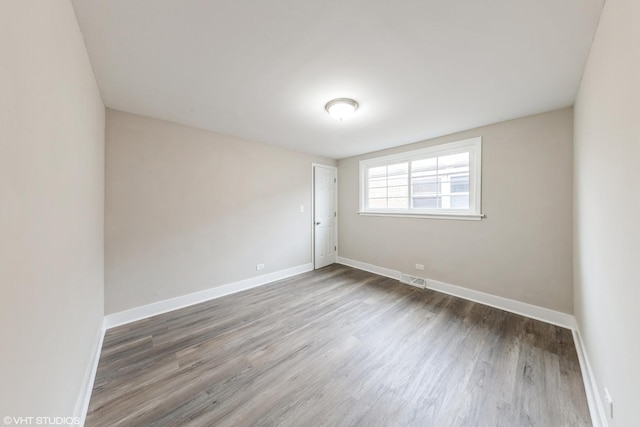 spare room featuring visible vents, baseboards, and wood finished floors