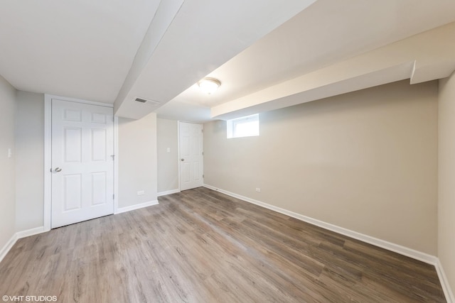 basement featuring visible vents, baseboards, and wood finished floors