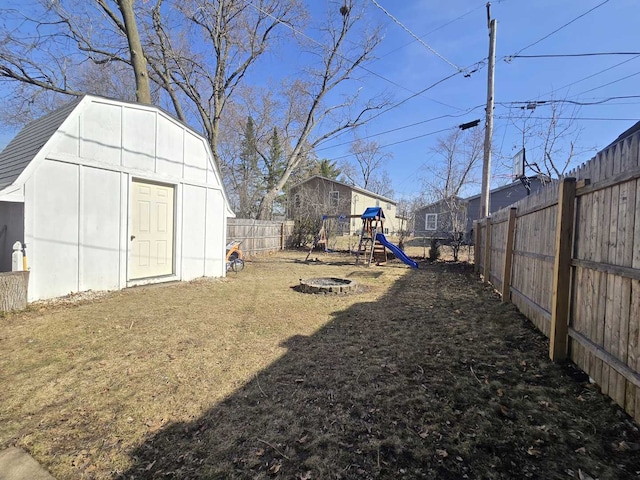 view of yard with an outbuilding, a playground, a fenced backyard, and a shed