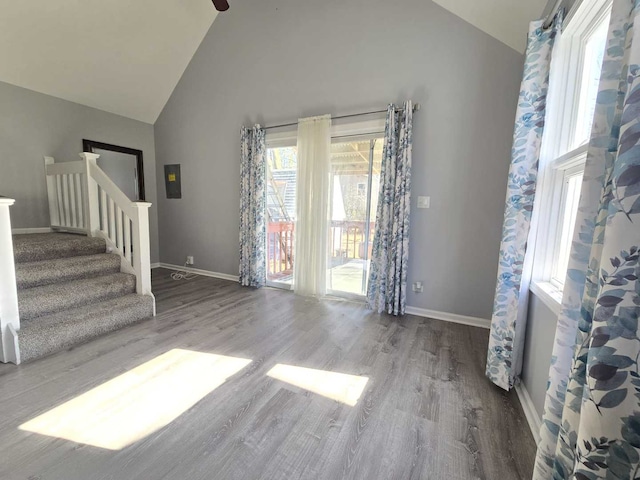 interior space featuring stairway, high vaulted ceiling, baseboards, and wood finished floors