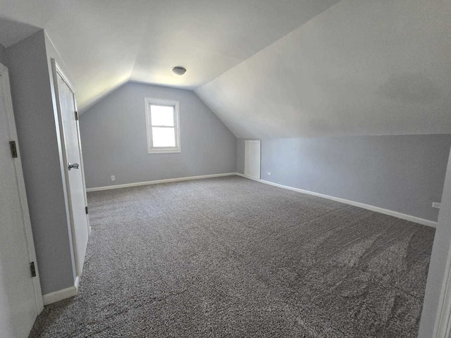 additional living space with vaulted ceiling, baseboards, and carpet floors