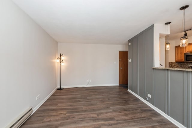 unfurnished living room featuring baseboards, baseboard heating, and dark wood finished floors