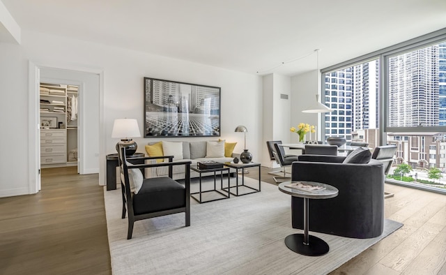 living room with plenty of natural light, wood-type flooring, baseboards, and expansive windows