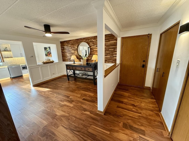 hallway with ornamental molding, a textured ceiling, and dark wood-style flooring