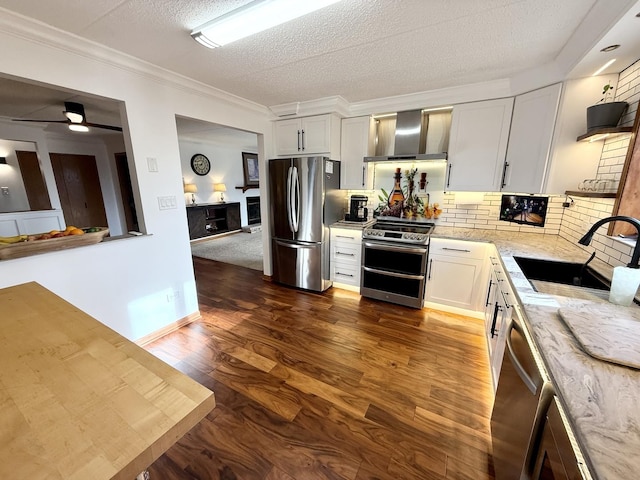 kitchen with light stone countertops, a sink, stainless steel appliances, dark wood-type flooring, and wall chimney exhaust hood