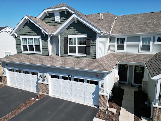 view of front of home with a garage, driveway, and a shingled roof