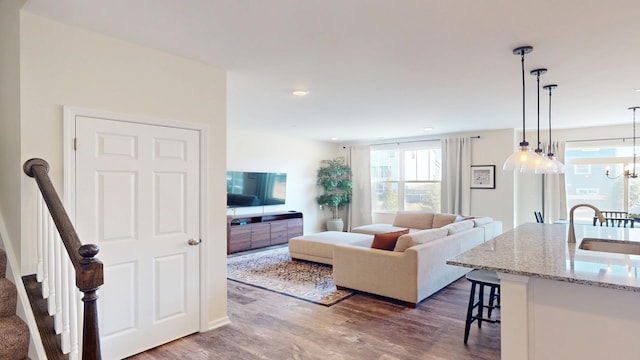 living room featuring an inviting chandelier, stairway, recessed lighting, and dark wood-style flooring