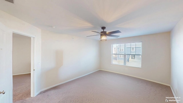 spare room featuring baseboards, a ceiling fan, and carpet