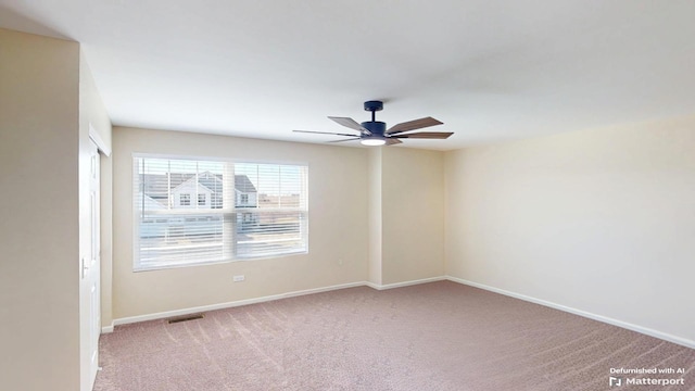 carpeted spare room with visible vents, baseboards, and a ceiling fan