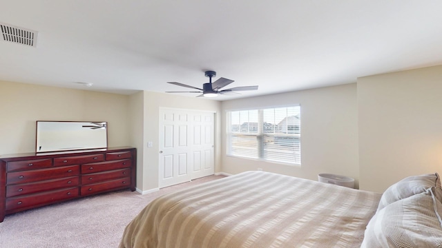 bedroom with visible vents, baseboards, light colored carpet, a closet, and a ceiling fan