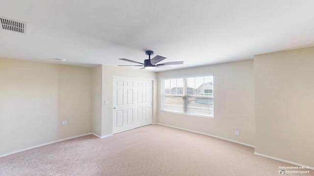 unfurnished bedroom featuring a ceiling fan, baseboards, visible vents, a closet, and light colored carpet