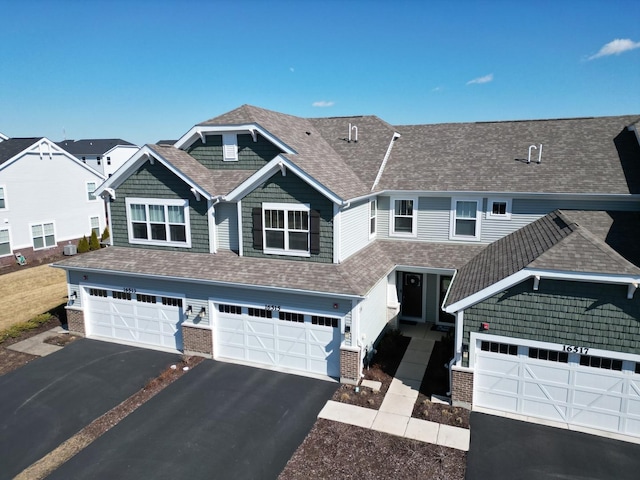 view of front of property featuring brick siding, driveway, and a shingled roof