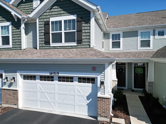 view of front of house featuring a garage, roof with shingles, and driveway