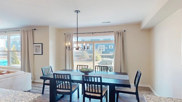 dining room with a notable chandelier, wood finished floors, visible vents, and baseboards