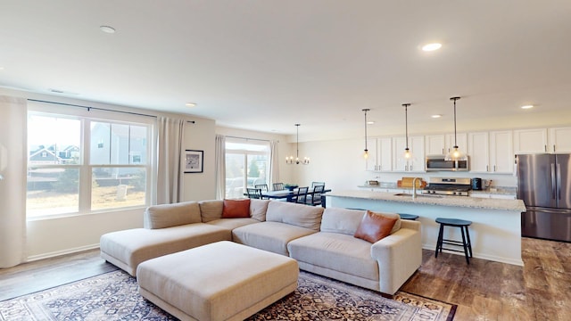 living area featuring visible vents, dark wood-type flooring, recessed lighting, an inviting chandelier, and baseboards