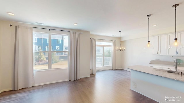 kitchen with wood finished floors, baseboards, hanging light fixtures, white cabinets, and a chandelier