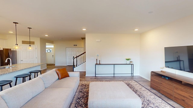 living room featuring visible vents, recessed lighting, stairway, light wood finished floors, and baseboards