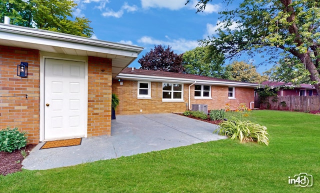 rear view of house featuring brick siding, a patio area, a yard, and fence