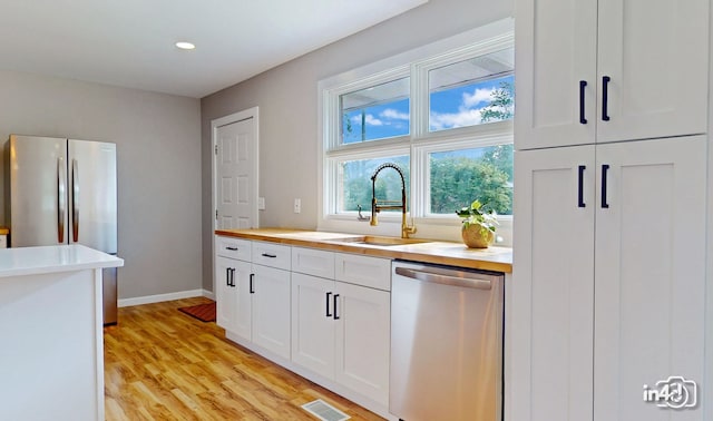 kitchen with visible vents, light wood-type flooring, stainless steel appliances, white cabinetry, and a sink