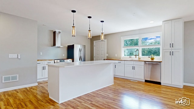 kitchen featuring visible vents, light wood-style flooring, white cabinets, stainless steel appliances, and wall chimney exhaust hood